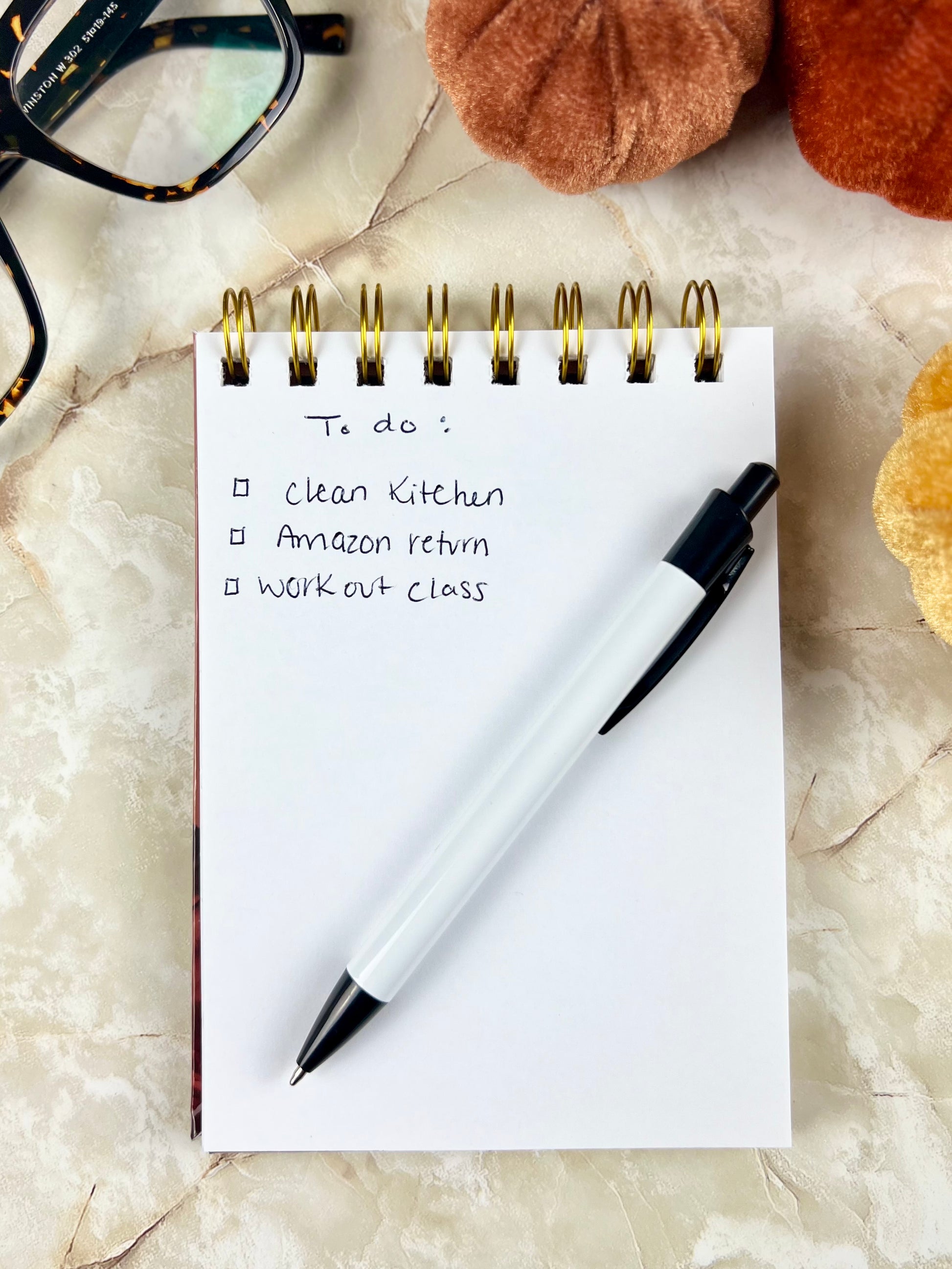Notebook with a to-do list and a pen on a marble surface