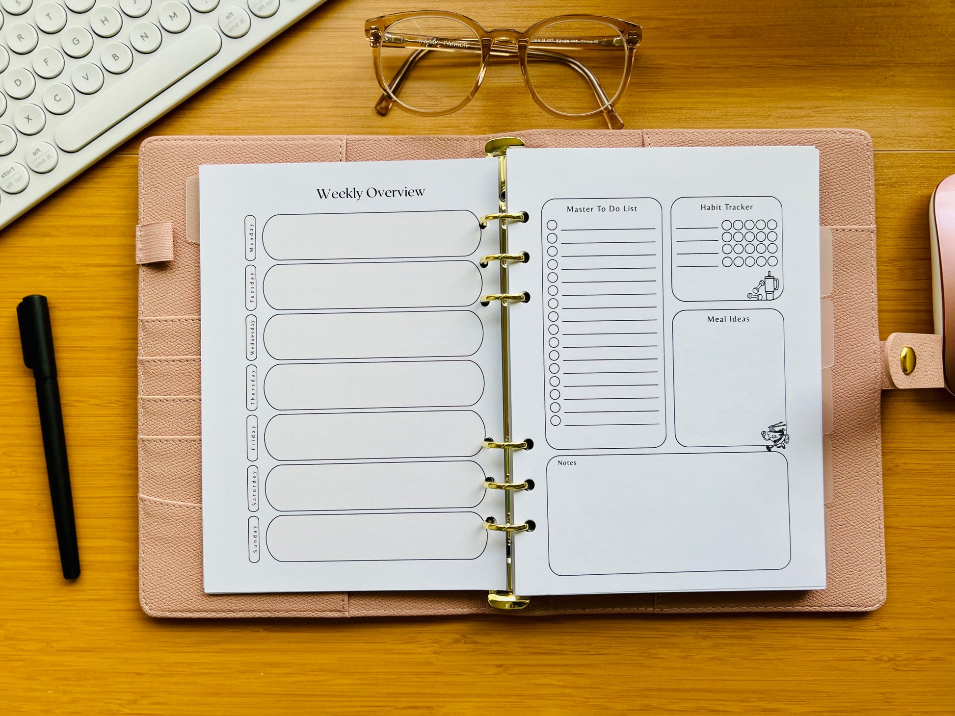 Open planner with weekly overview pages on a wooden desk with glasses and a pen.