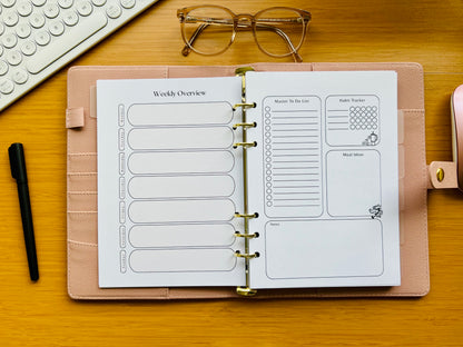 Open planner with weekly overview pages on a wooden desk with glasses and a pen.