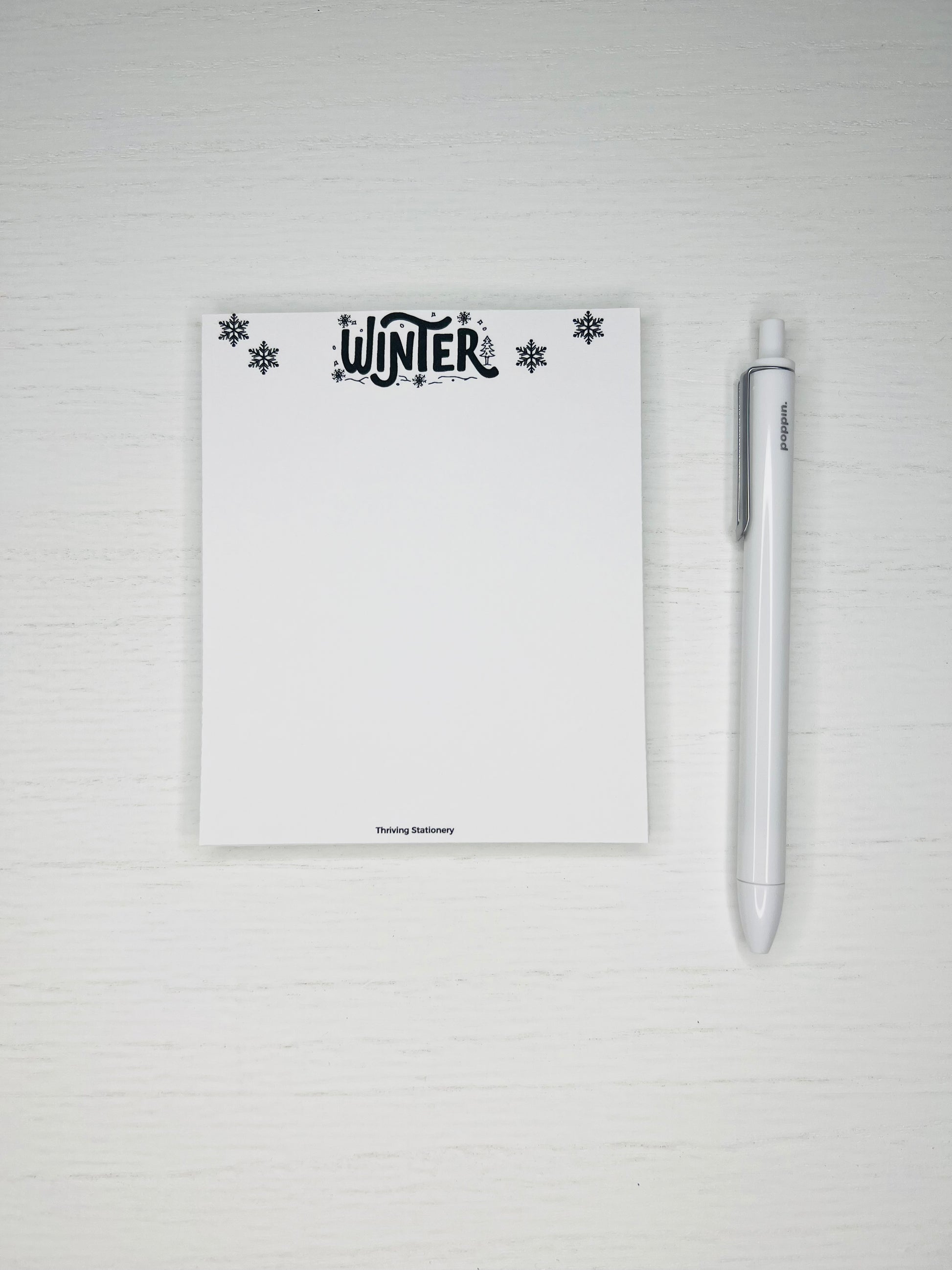 Minimal winter-themed notepad with black snowflakes and “Winter” lettering at the top, blank white writing space below.